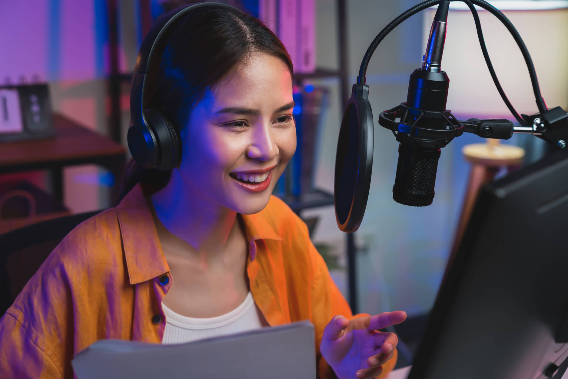 A woman wearing headphones and using her laptop to record a podcast after she decided to hire a content manager.