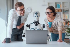 In a scenario depicting AI in digital marketing, a robot sits at a PC flanked by two professionals in an office, symbolizing the integration of artificial intelligence in marketing strategies.