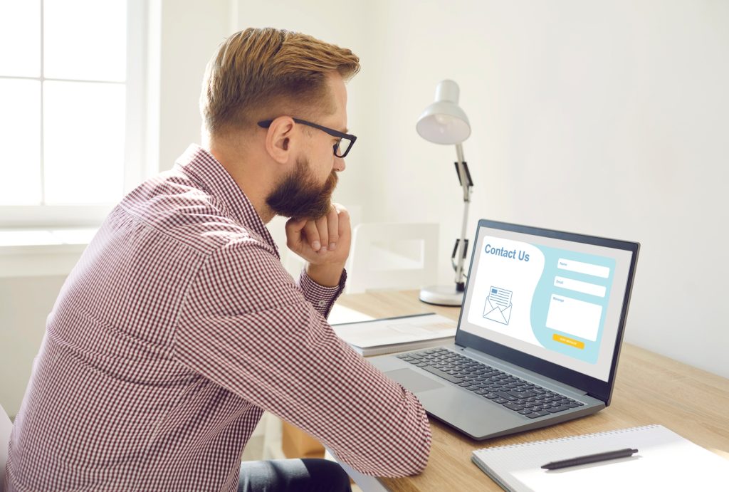 A man intently looking at a computer screen displaying various types of landing pages.