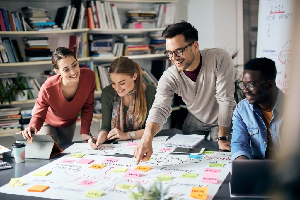 A team of small business marketing consultants, consisting of diverse genders, sits around a table discussing strategic plans.