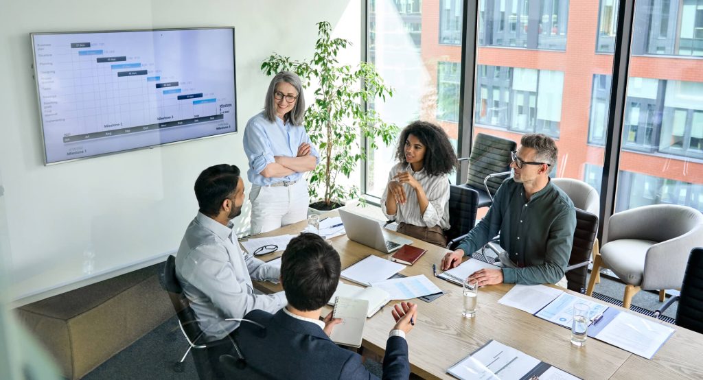 A woman presenting something to a team, discussing the benefits of a fractional CMO salary.