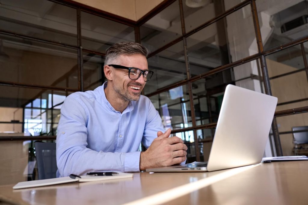 A man looking into a computer screen, researching a fractional CMO salary.