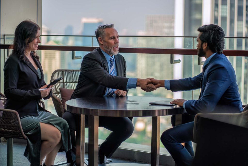 A professional meeting where two executives are shaking hands, symbolizing a successful agreement between a fractional CEO and a client.