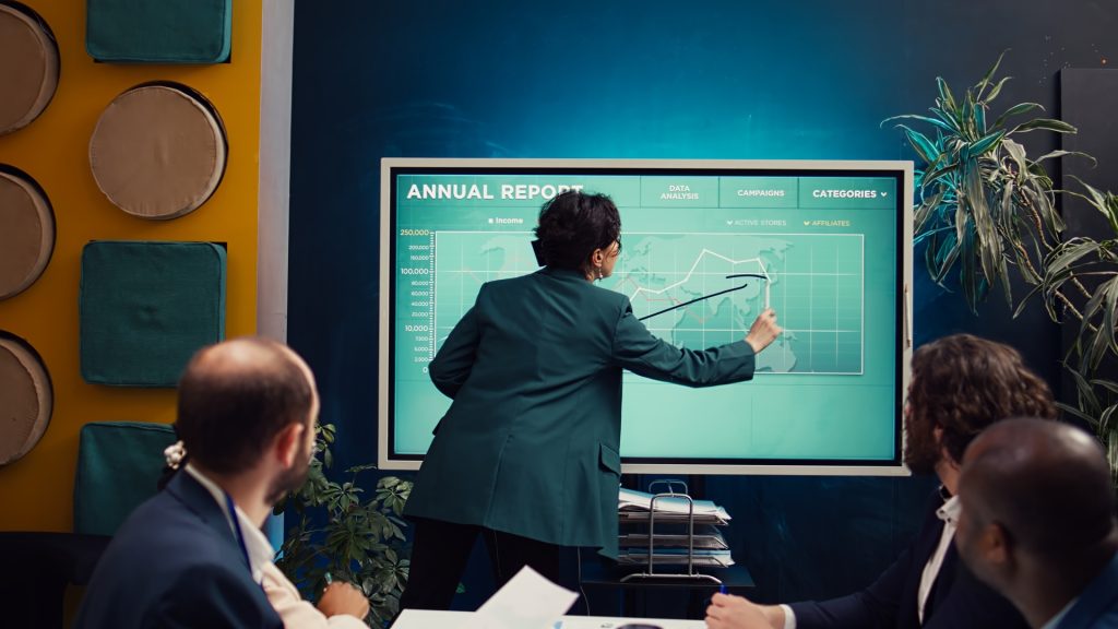 An executive presenting detailed analytics on a digital board to a team, representing the role of fractional executives in driving growth and informed decision-making within companies.