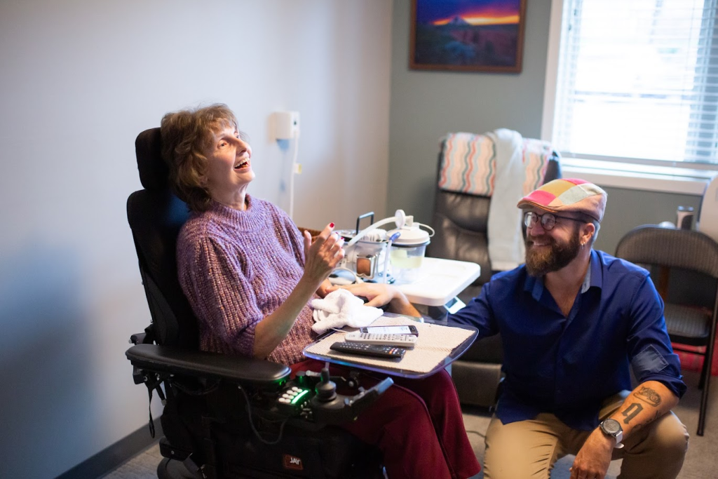 A filmmaker interviewing a long-term care resident in her room