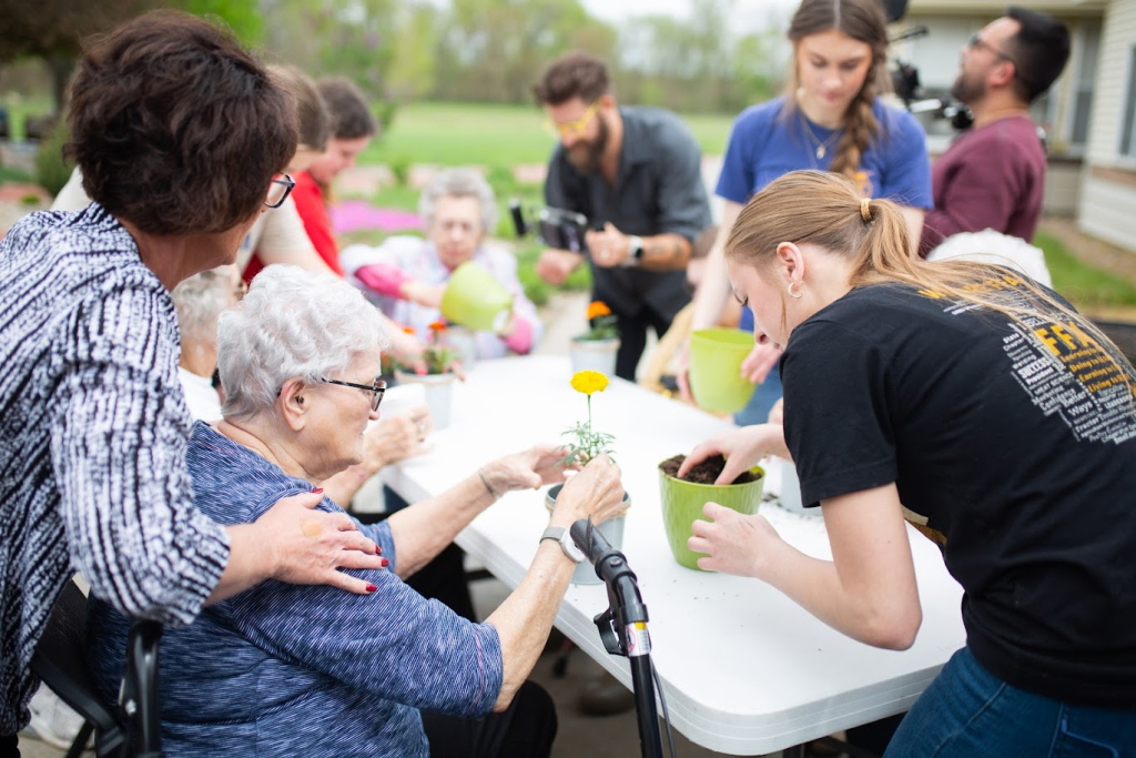 Care community residents and volunteers potting flowers together outdoors