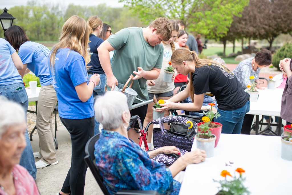 Residents and staff planting flowers together at outdoor tables