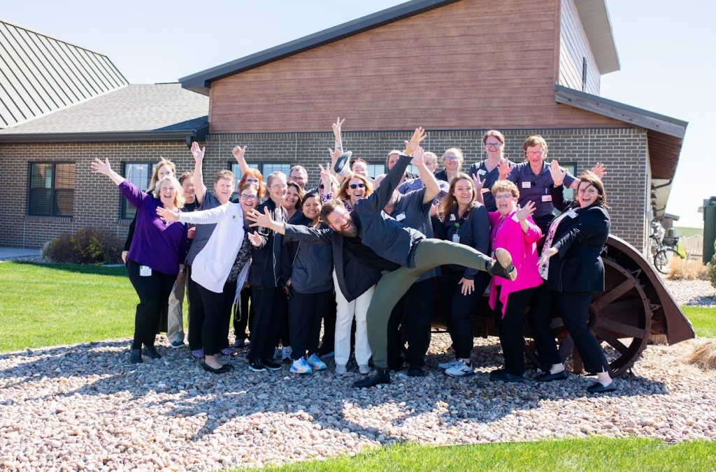 Care community staff and residents celebrating together outside the building