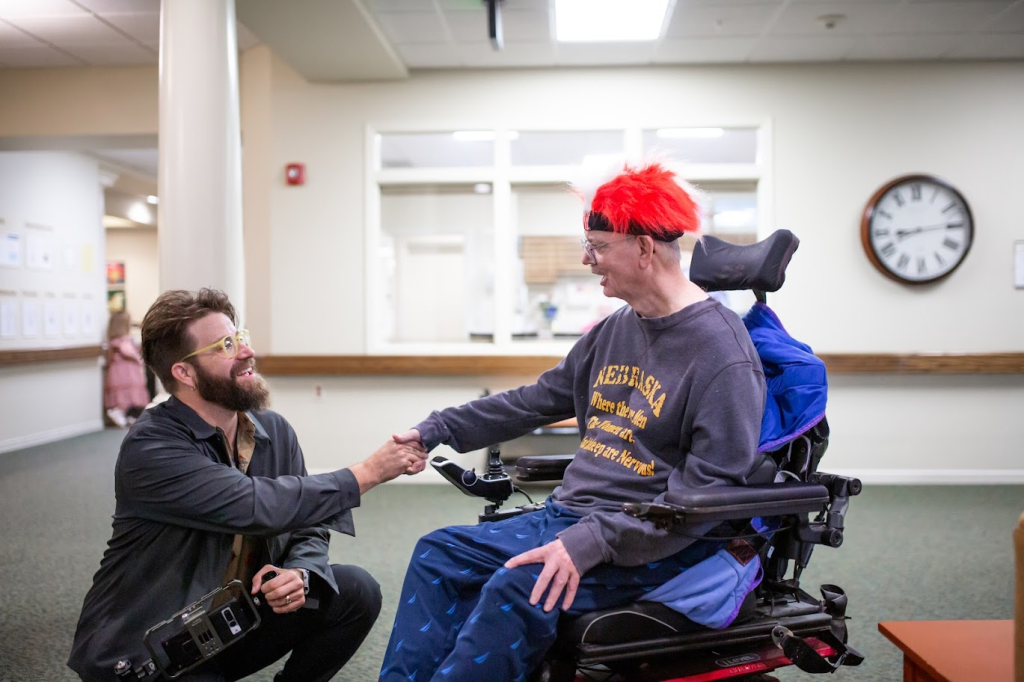 A documentary filmmaker greeting a resident using a wheelchair