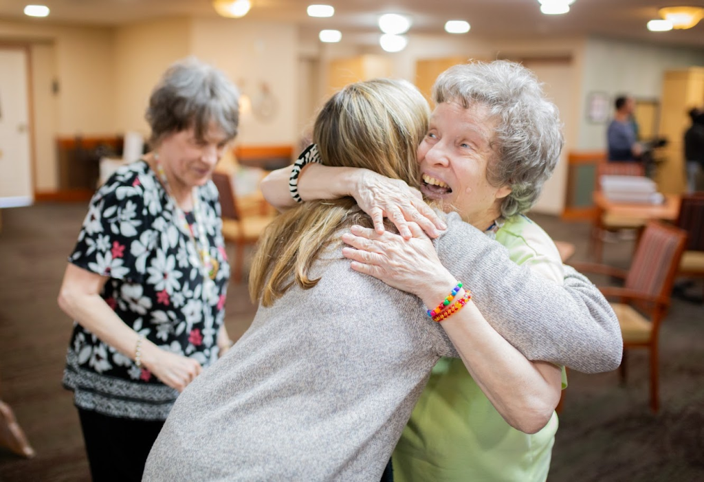 Residents embracing in a care community lounge