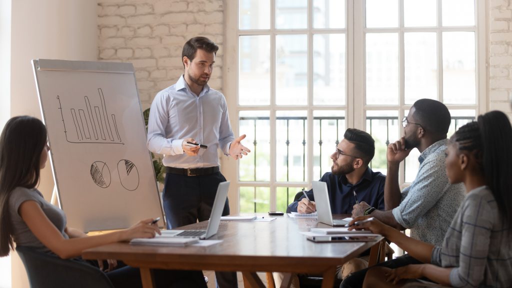 A group of professionals in a meeting, discussing charts and graphs, representing the process to hire a marketing expert.