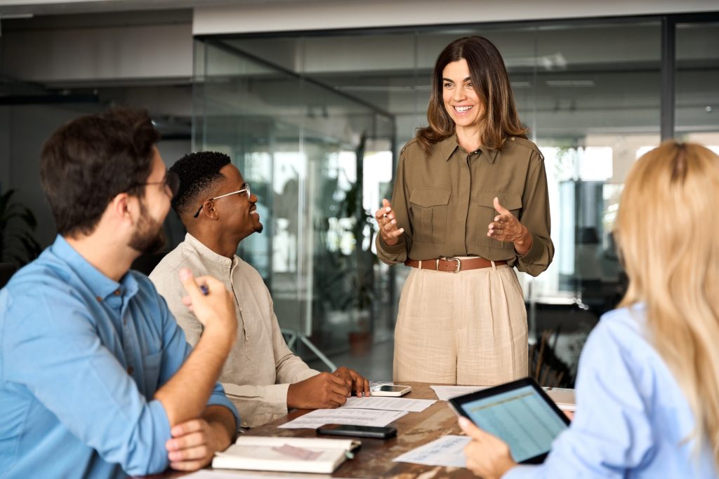 A woman leading a business meeting, explaining strategies, exemplifying the importance of hiring a marketing expert.