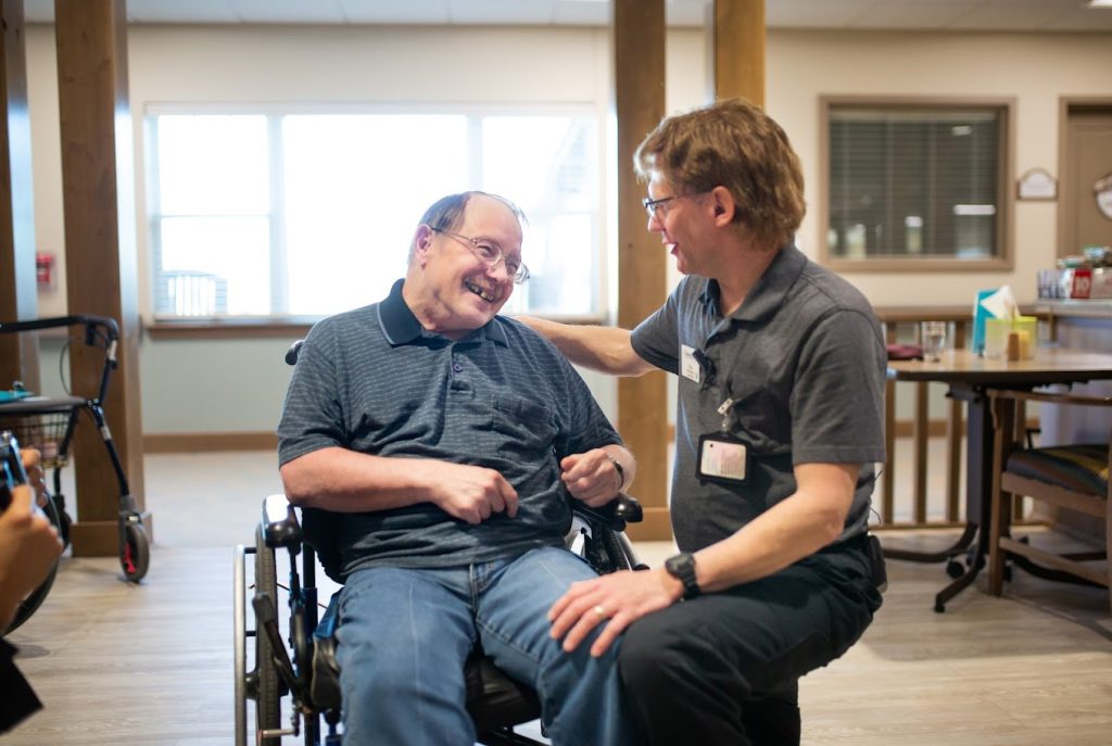 A caregiver sharing a laugh with a resident using a wheelchair