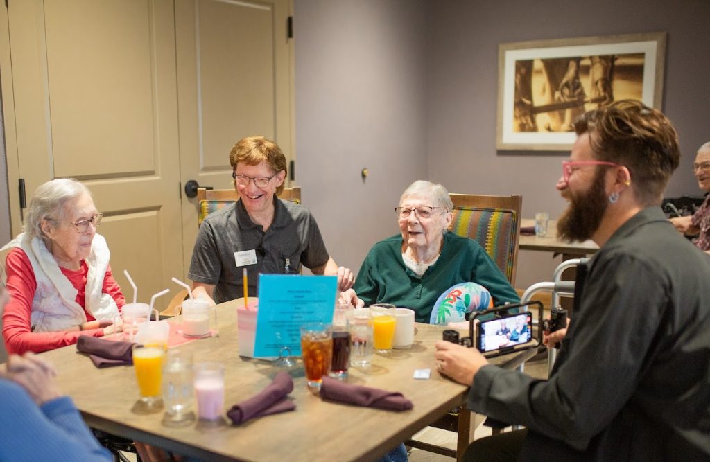 Residents and staff around a table during a filmed conversation