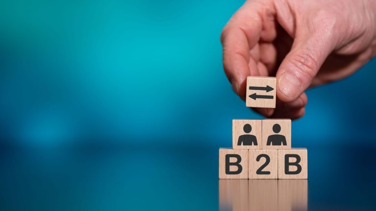 A hand placing lettered blocks spelling B2B on a desk