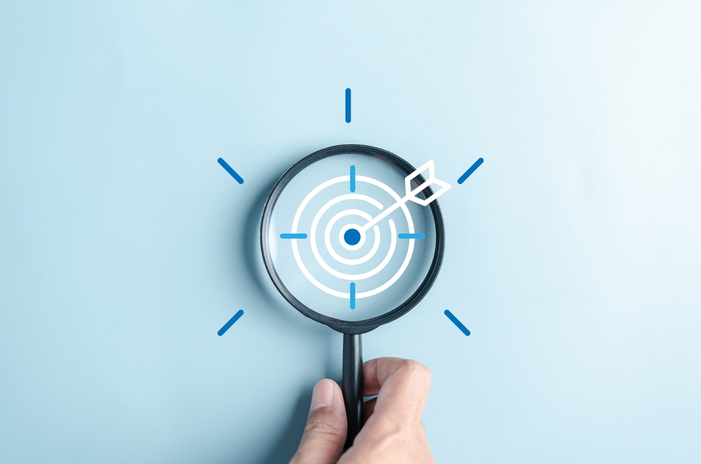 Marketing leadership and the future: A magnifying glass focusing on a target with an arrow, symbolizing strategic vision and goal-setting.