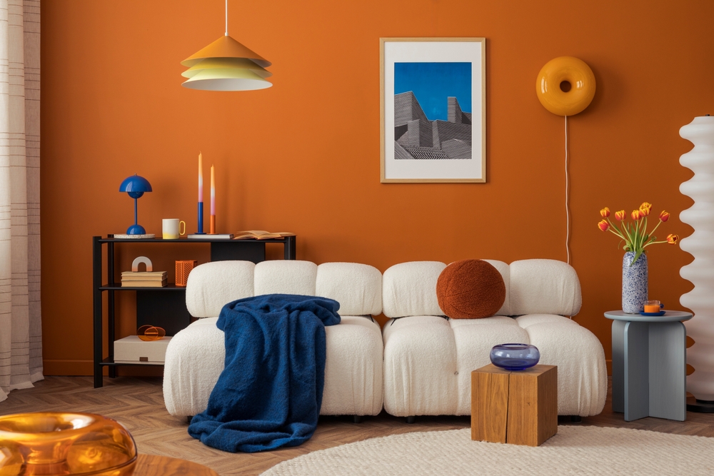 Modern living room with orange accent wall, contemporary furniture, and architectural artwork — ideal visual for marketing for architecture firms focusing on marketing theirs services.