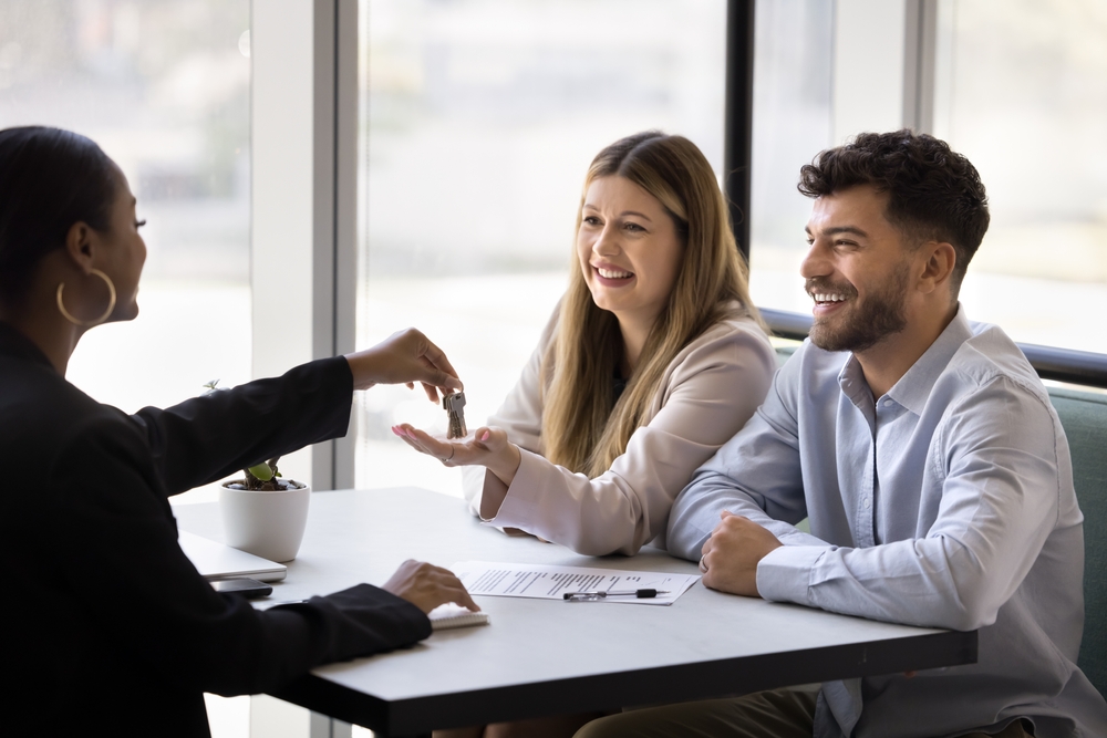 A corporate housing manager handing keys to company representatives after signing a lease, illustrating how to market corporate housing effectively.