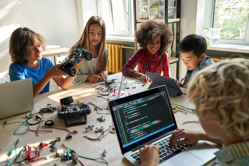 Group of students working on robotics and coding projects in a classroom, showcasing innovative marketing strategies for schools that highlight STEM education.