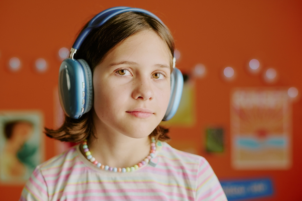 Young student wearing headphones in a colorful classroom, representing creative marketing for schools focused on engaging learning environments.