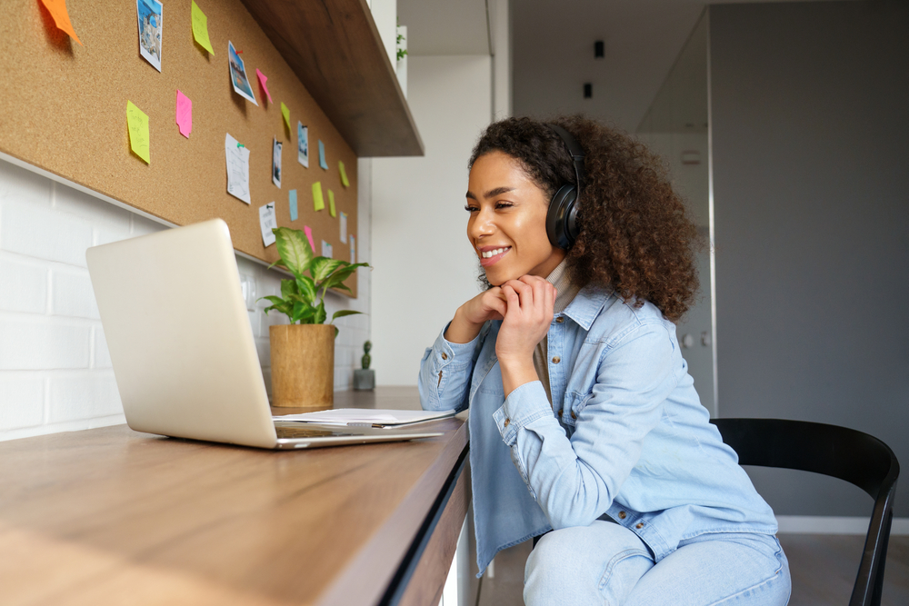 Young professional wearing headphones and working on a laptop at home, illustrating how modern marketing department teams collaborate remotely and manage digital projects.