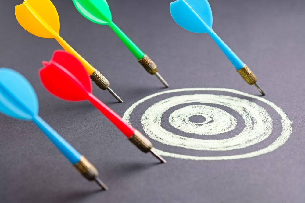 Colorful darts missing a chalk-drawn target on a dark surface, representing common digital marketing mistakes and the challenge of missing strategic goals.