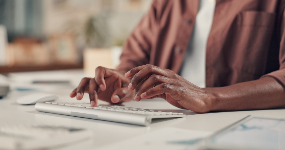 Hands typing on a keyboard during digital strategy work, representing how the best SEO solutions rely on clear structure, user intent, and optimized content.