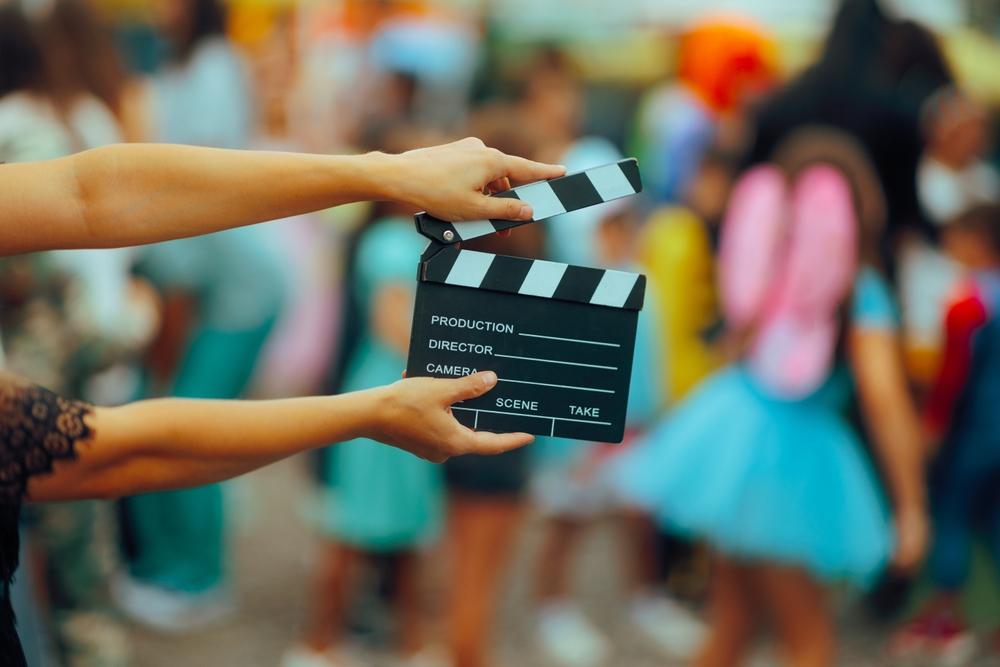 A person holding a film clapperboard on a colorful set, symbolizing creative content creation and illustrating how to market a video production company through behind-the-scenes visuals.