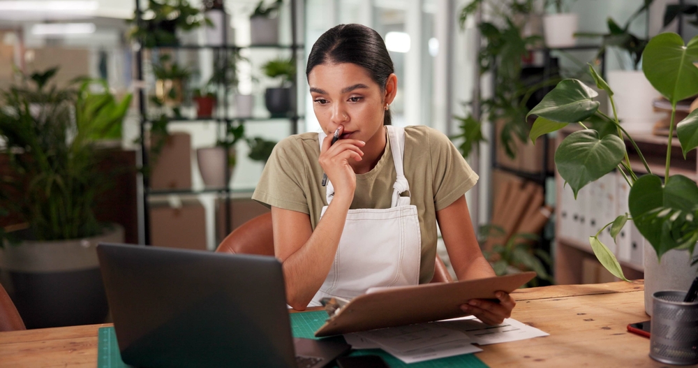 Entrepreneur working at a desk with a laptop and tablet, planning strategy and analysis for small business digital marketing.