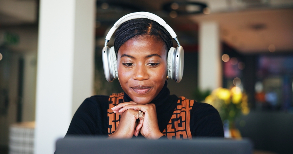 Professional wearing headphones and working on a laptop in a modern workspace, illustrating inbound tactics such as content consumption, lead nurturing, and focused digital engagement.