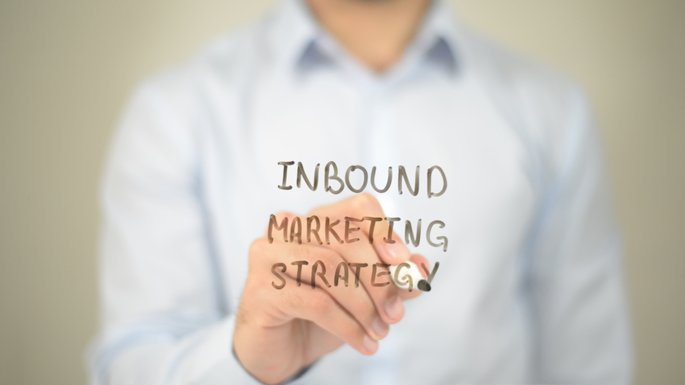 Person writing “Inbound Marketing Strategy” on a transparent board, representing inbound marketing for SaaS companies focused on strategy, growth, and customer acquisition.
