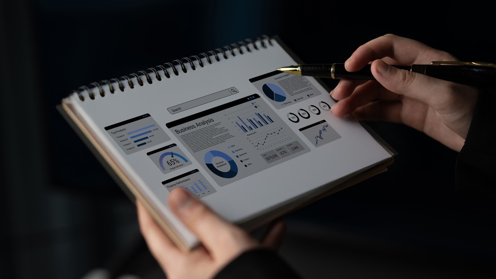 A professional reviews business analytics and performance charts in a notebook, using data-driven insights to support strategic planning and thought leadership.