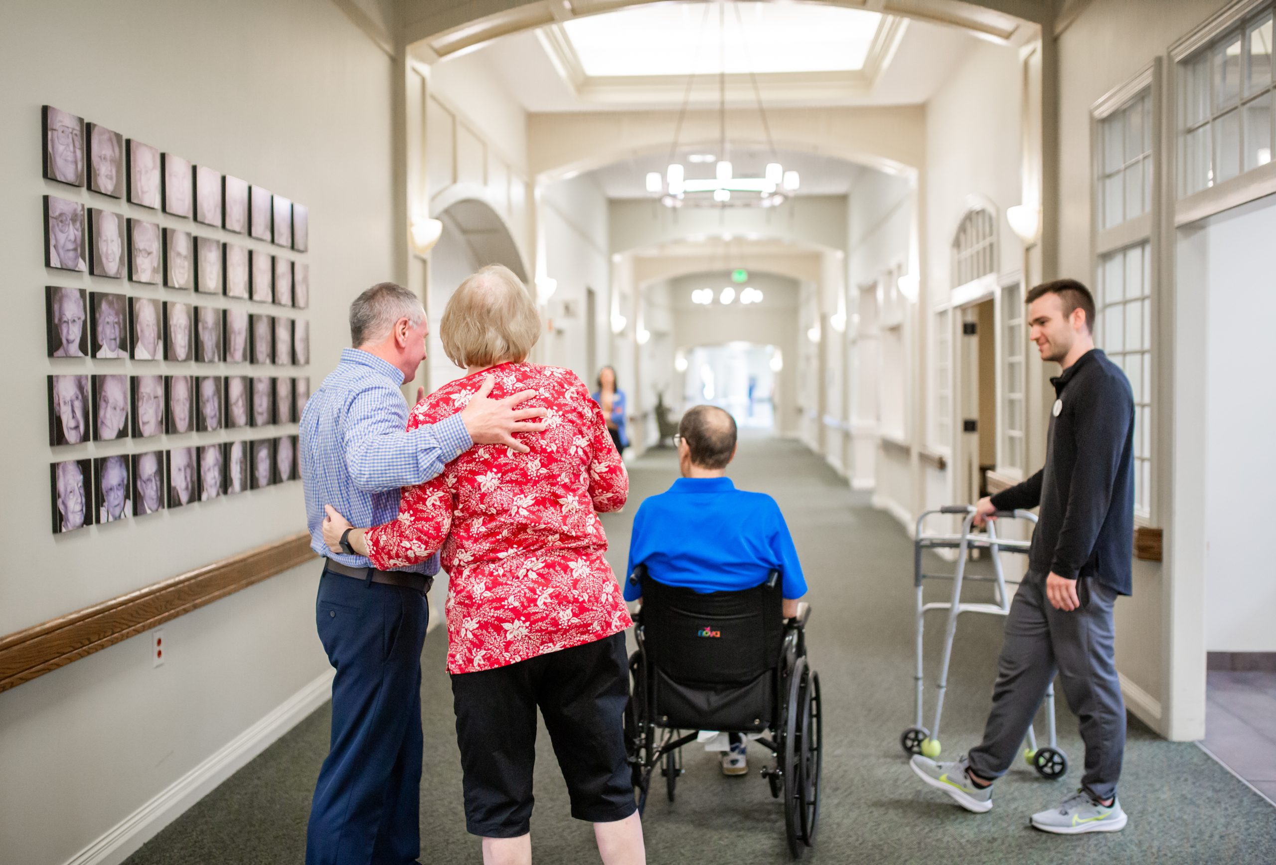 Residents, family and staff walking a hallway in a long-term care community