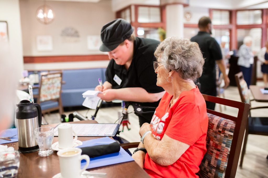 A dining-room server taking a resident's order, filmed for People Worth Caring About