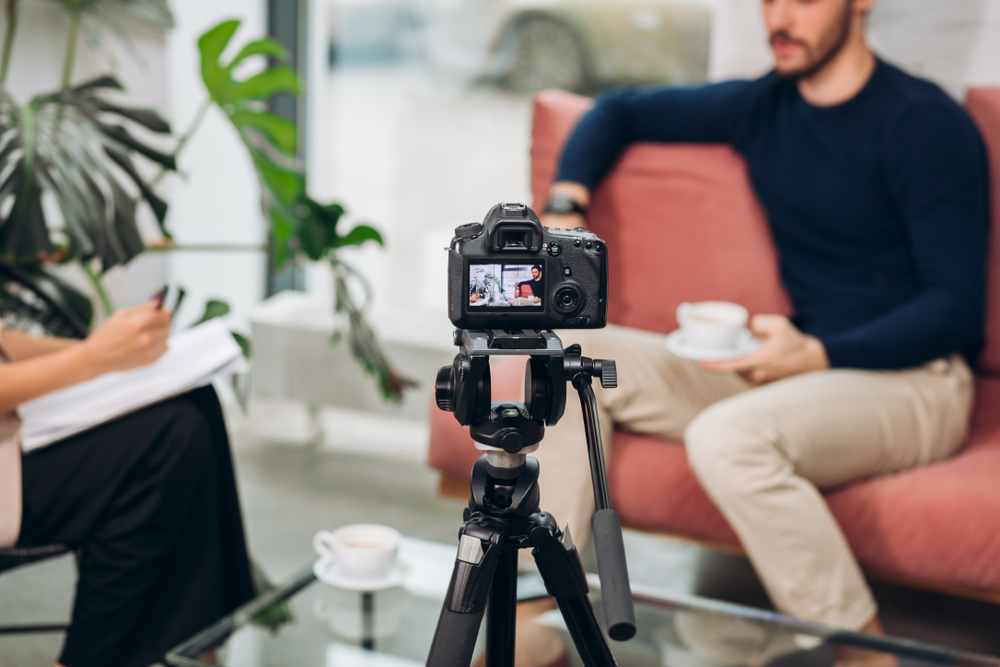 Camera recording an interview between a reporter and a local business owner, illustrating how to get local press coverage through community stories, media interviews and local news outreach.