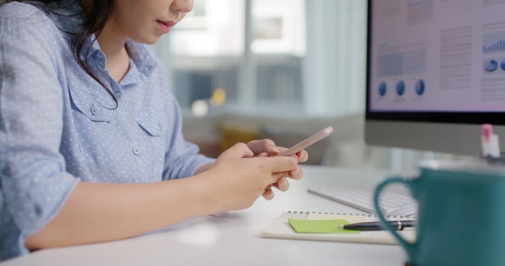 Healthcare marketer using a smartphone beside analytics dashboards, illustrating digital healthcare marketing across digital platforms and data-driven outreach.