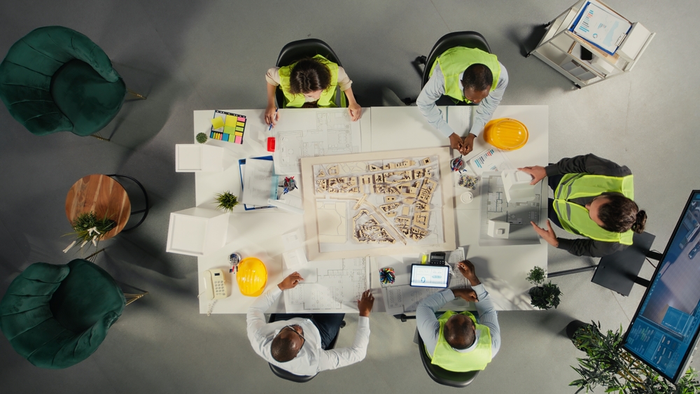 Construction team reviewing architectural plans and project models from above, illustrating a collaborative construction marketing strategy focused on planning, coordination, and growth.