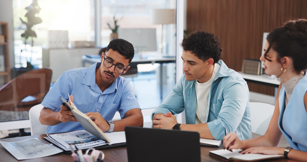 Team reviewing documents and campaign materials during a planning meeting, illustrating How to Pitch a Story to a Journalist with a clear angle, supporting information and a focused media strategy.