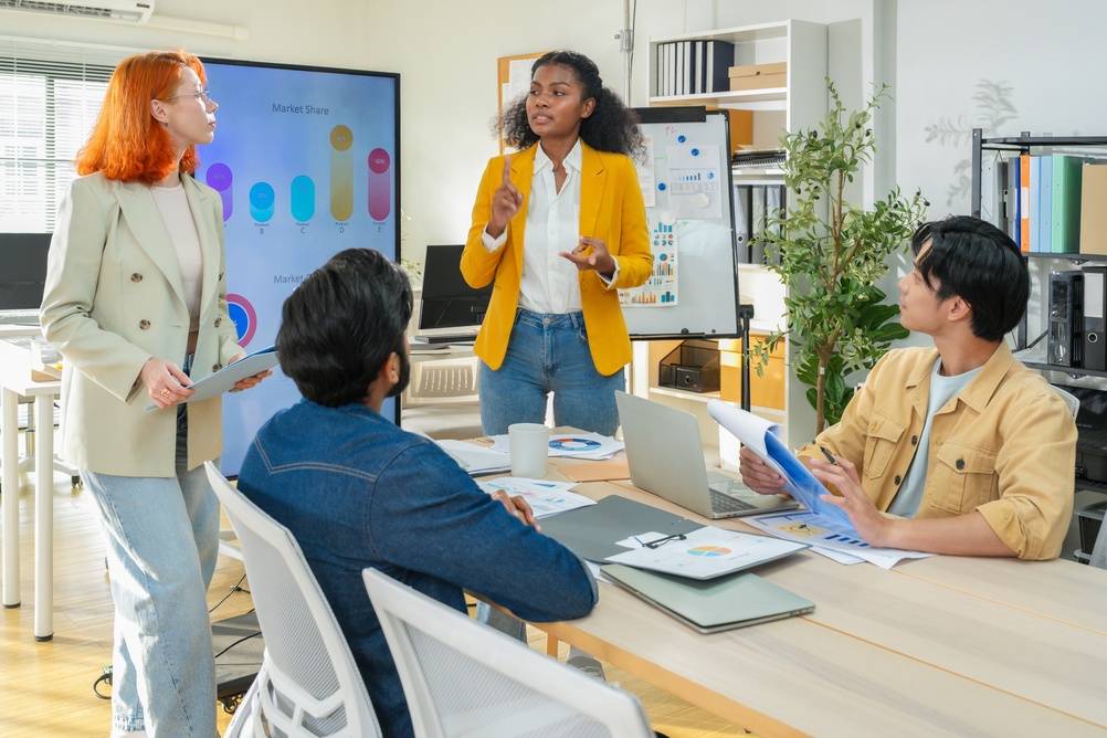 Marketing team discussing charts and market data during a strategy meeting, illustrating collaborative demand generation tactics for B2B growth.
