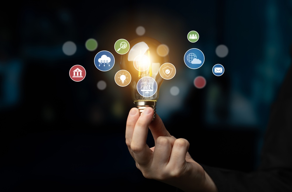 Hand holding a glowing lightbulb surrounded by business and communication icons, representing multiple demand generation channels and strategies.