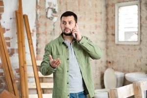 Contractor taking a work call on an indoor construction site, the moment where contractor lead generation pays off or stalls.