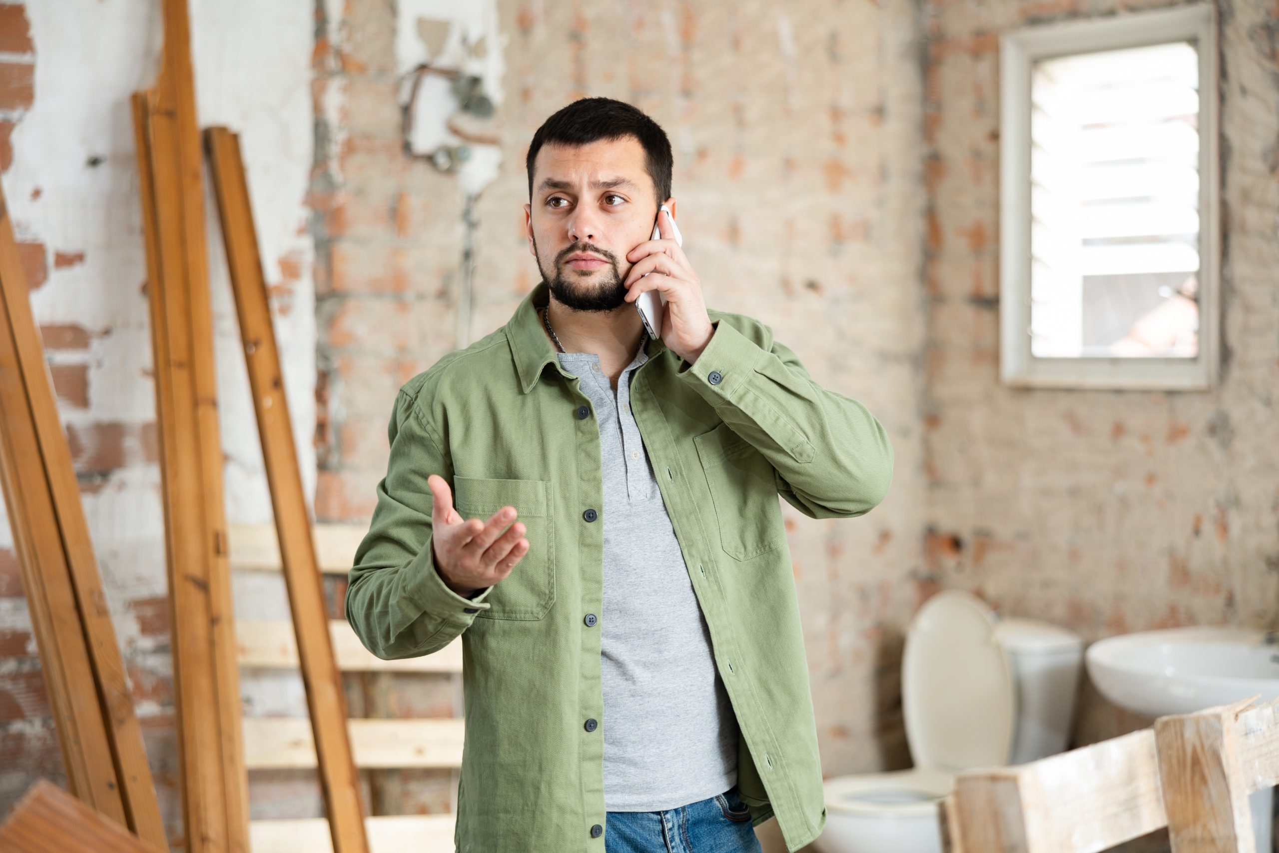 Contractor taking a work call on an indoor construction site, the moment where contractor lead generation pays off or stalls.