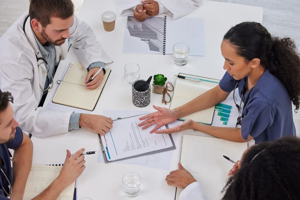 Overhead view of a healthcare team reviewing paperwork around a meeting table