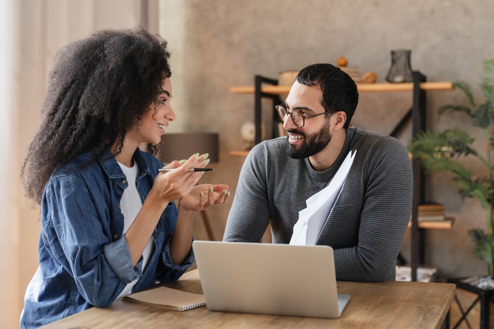 Two colleagues discussing a demand generation framework over a laptop